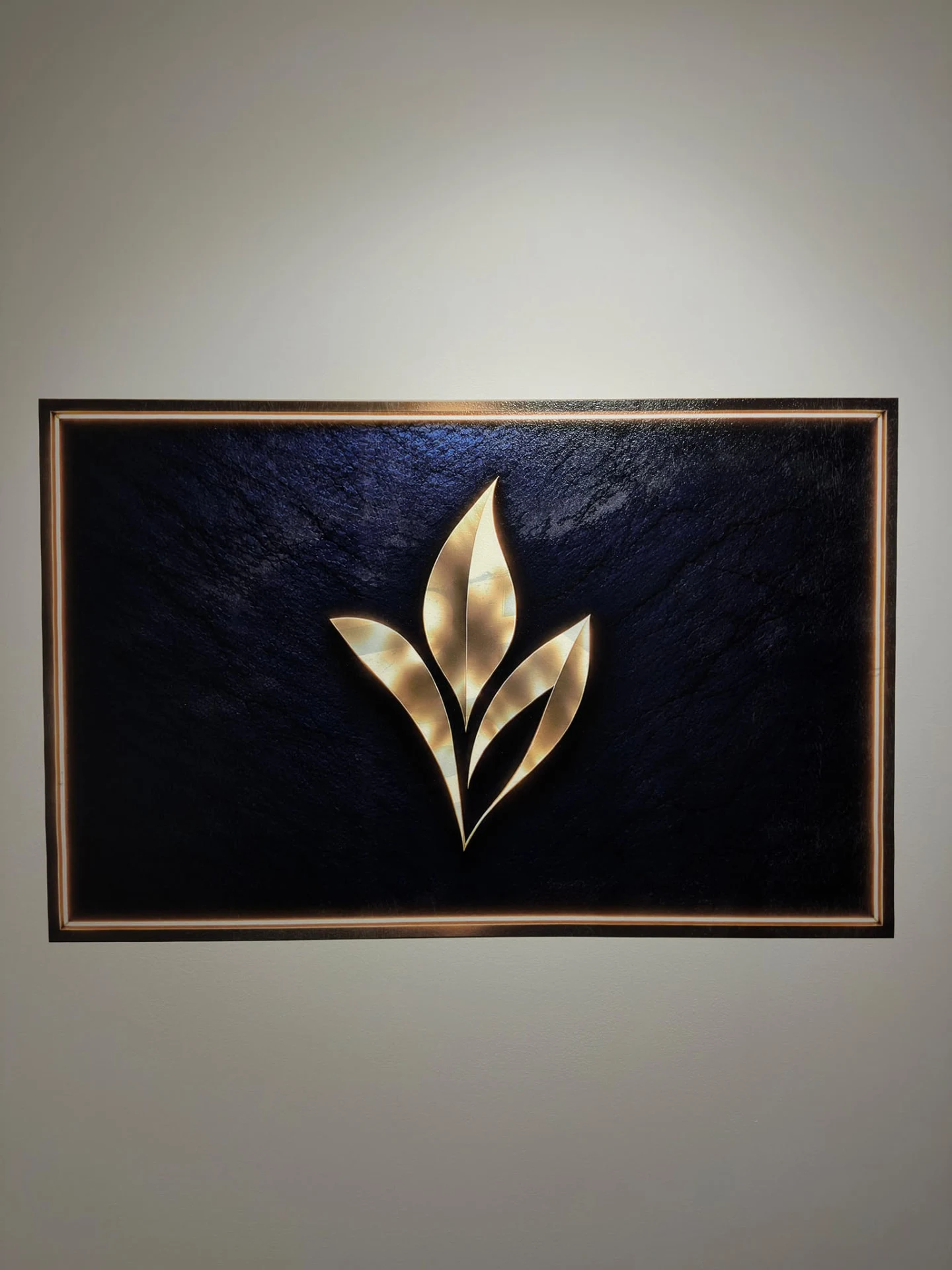 Gold floral motif printed onto a dark framed composition on the wall.
